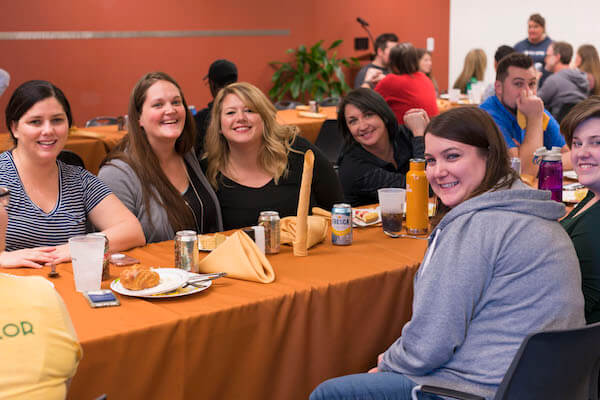 IMG: people sitting around the thanksgiving table smiling at the camera