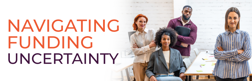 Four professionals in casual work attire, around a table, looking into the camera. Text on image reads Navigating Funding Uncertainty